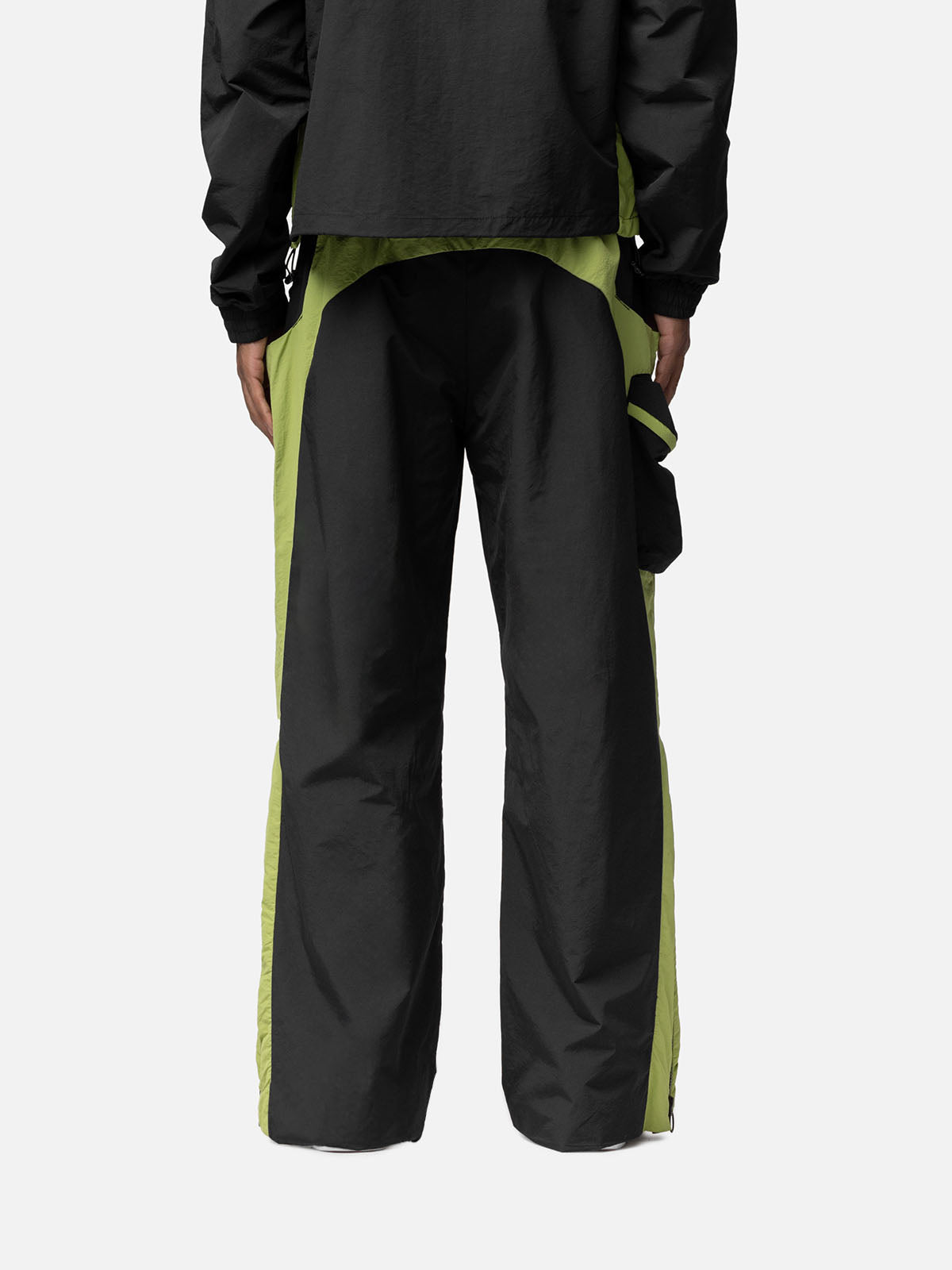 Back view of black with green side panels track pants, side pocket on the right side, zip pocket at the back, matching jacket.