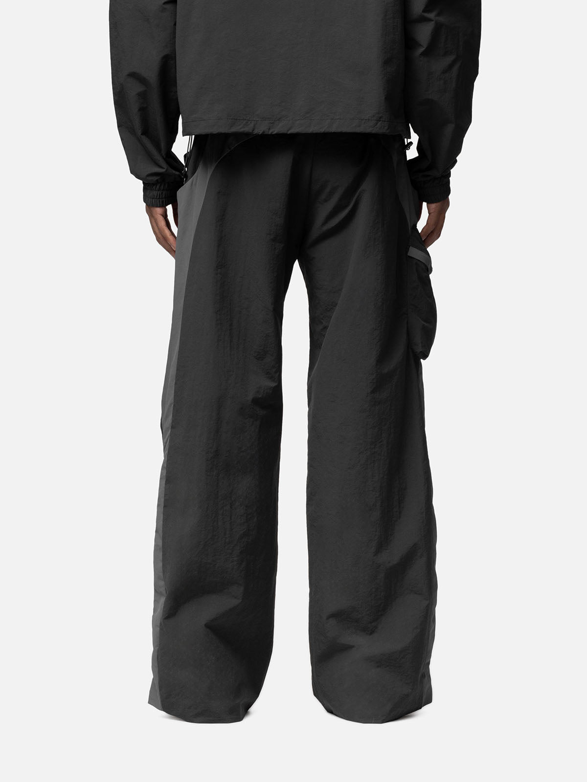 Back view of a charcoal with grey side panels track pants, side pocket on the right side, zip pocket at the back, matching jacket.