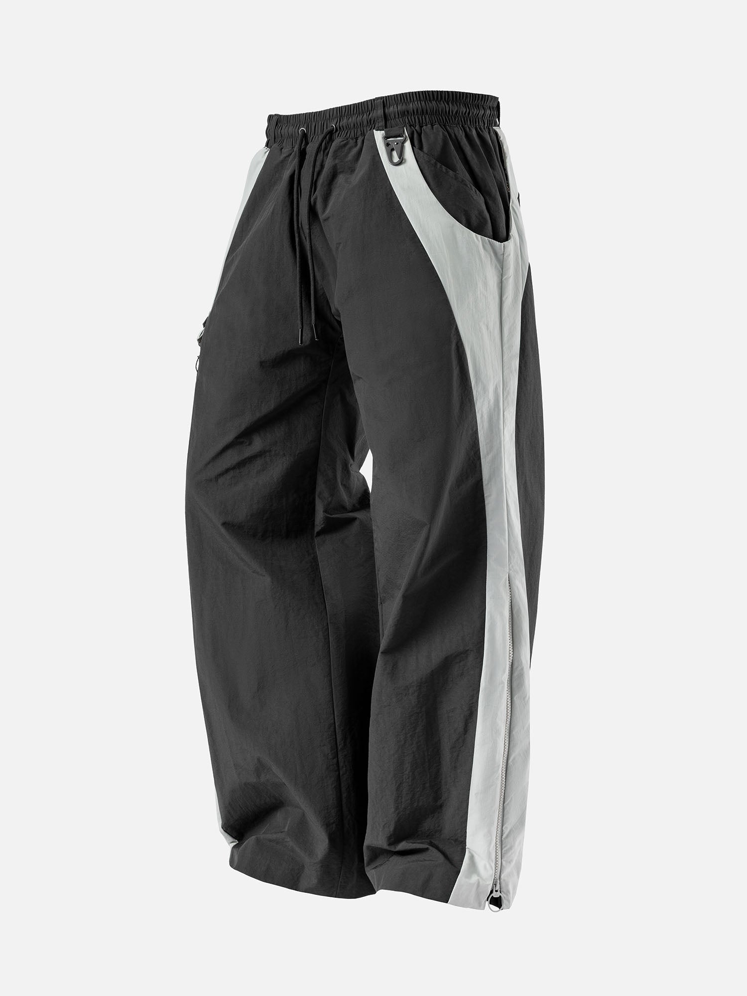 Black with white side panel track pants, featuring a decorative buckle at the waist, and a zip-up expandable seam to hem.