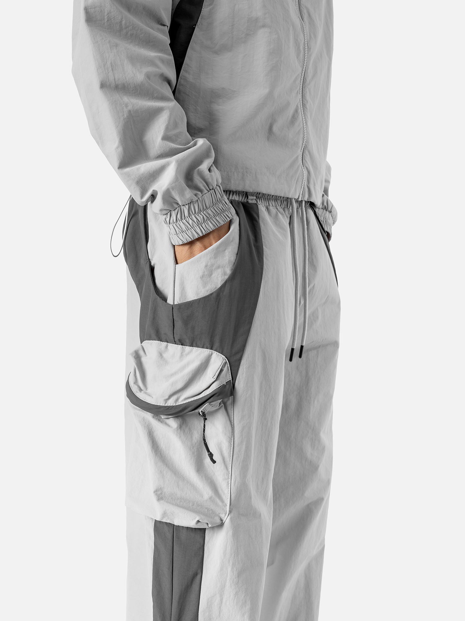 Close-up of the side pocket of a light grey with grey side panels track pants.