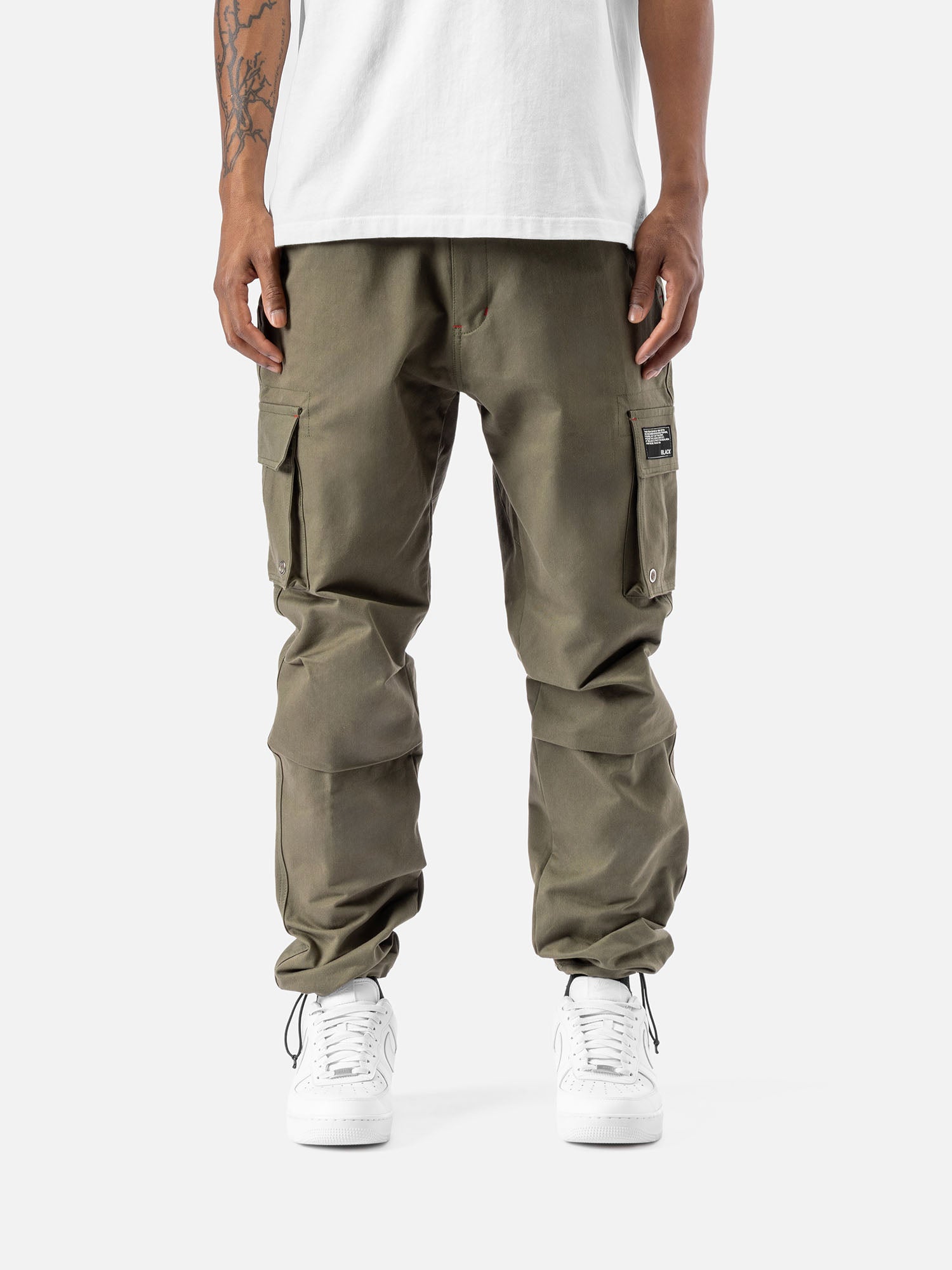 Forest cargo pants with side pockets, ankle drawstrings, paired with a white t-shirt, and white sneakers, showcasing streetwear style.