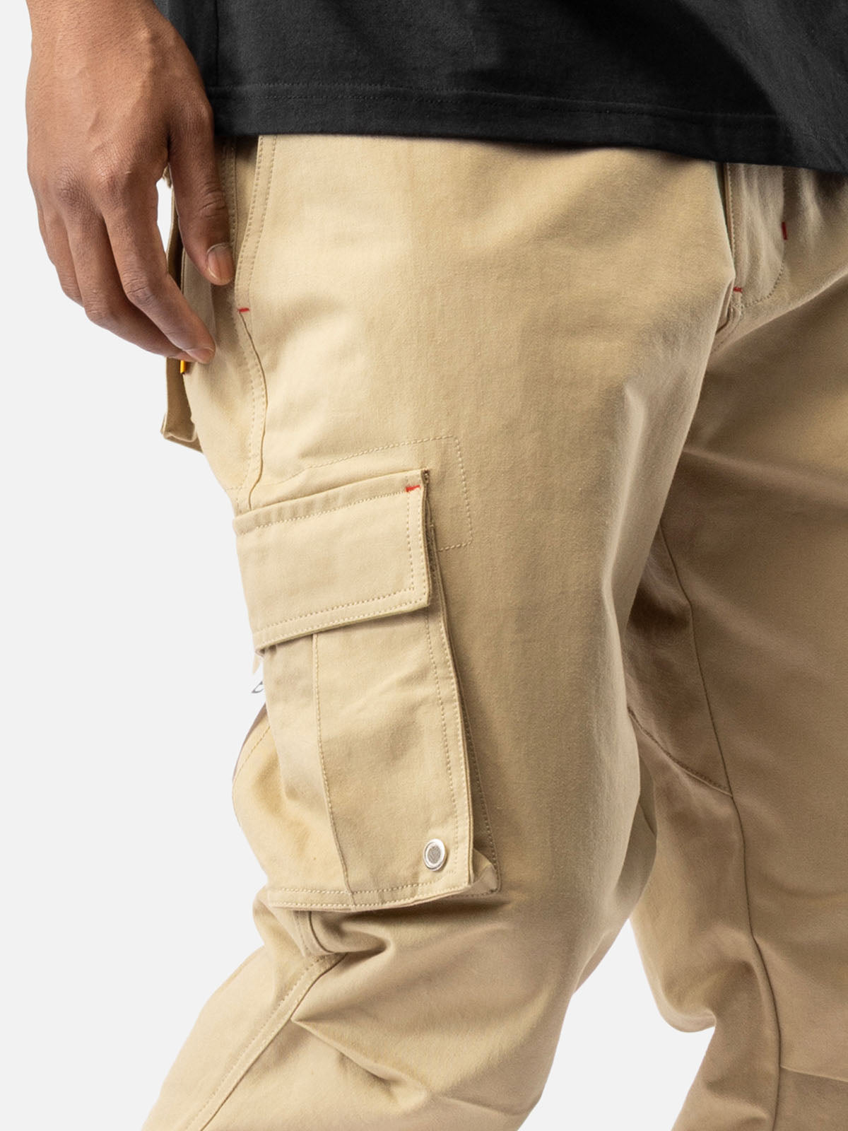 Close-up of a side pocket of khaki cargo pants with ankle drawstrings and simple back pockets.