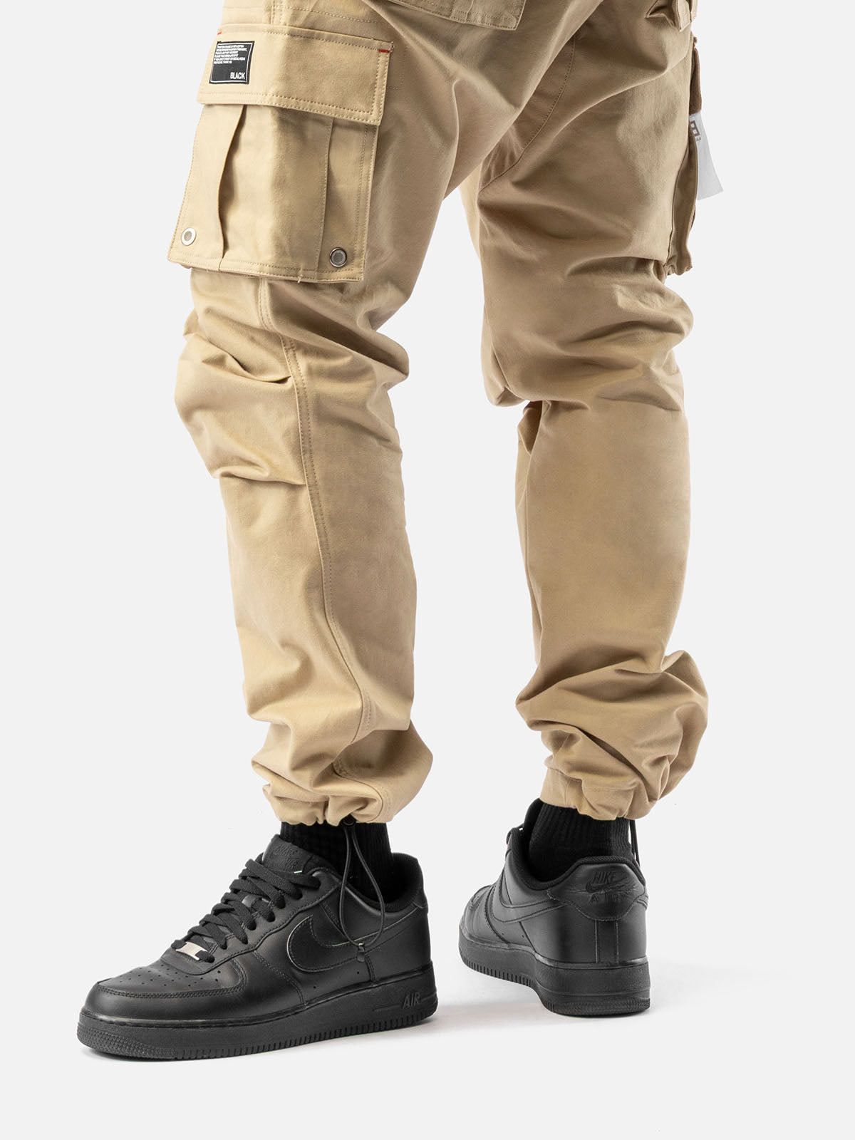 Close-up of ankle drawstrings of khaki cargo pants with side pockets and simple back pockets.