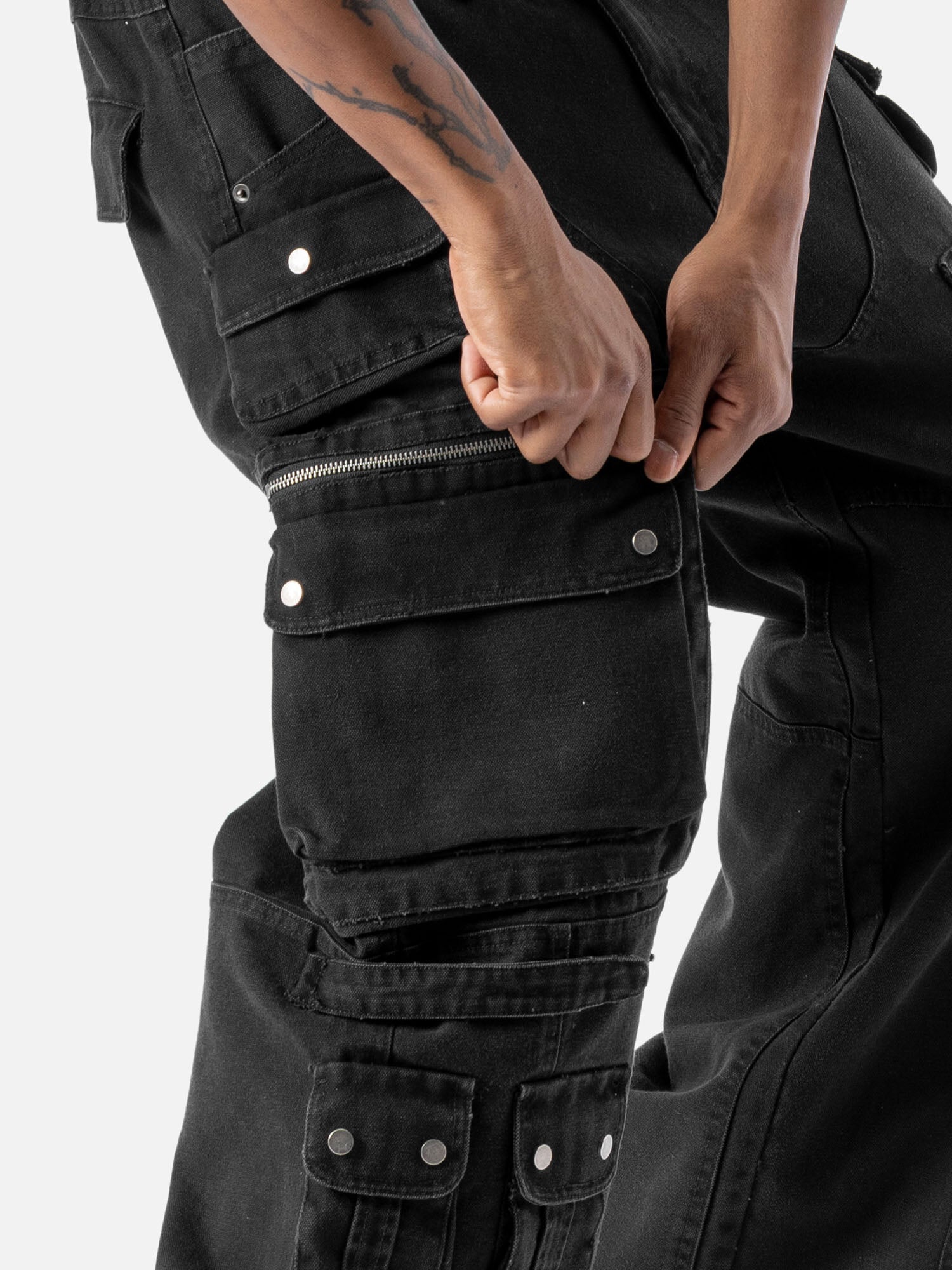 Close-up of a side pocket of black cargo pants with multiple functional pockets and a zipper detail.
