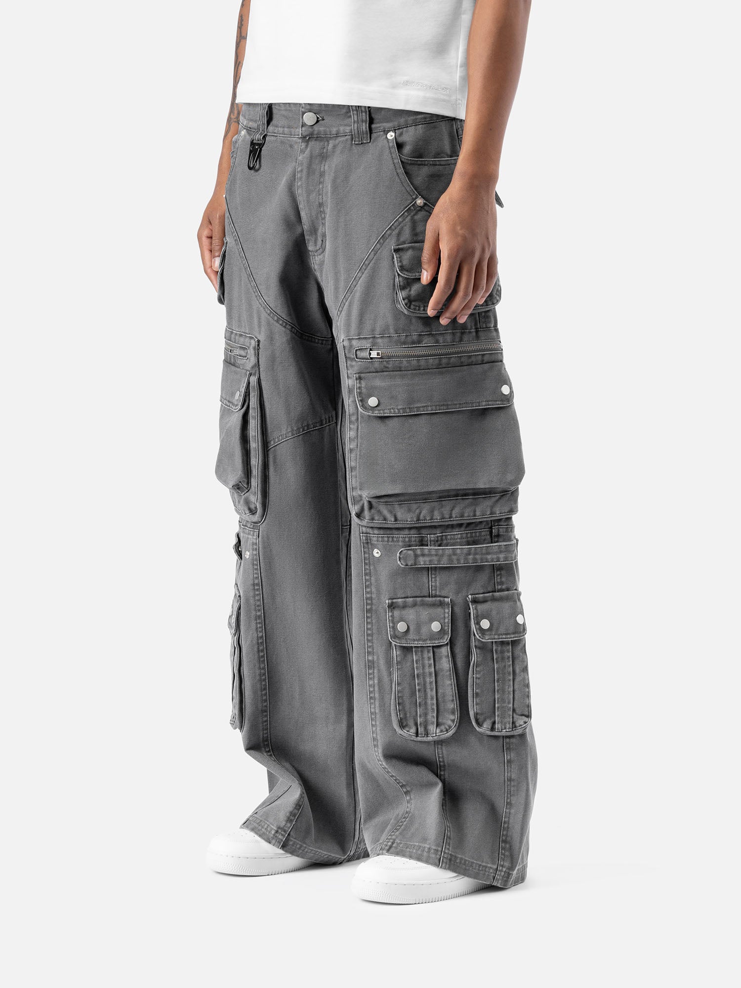Side view of grey cargo pants with multiple large pockets, a wide-leg cut, and paired with a white t-shirt and sneakers.